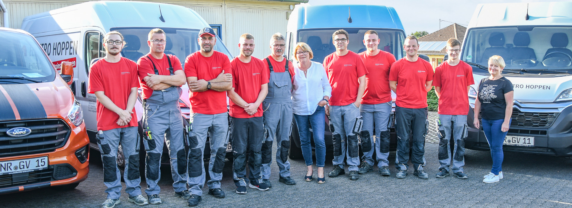 Team der Elektro Hoppen GmbH, bestehend aus 11 Mitarbeitenden, darunter 2 Frauen. Das Team steht vor den Firmenautos im Hof des Unternehmens.